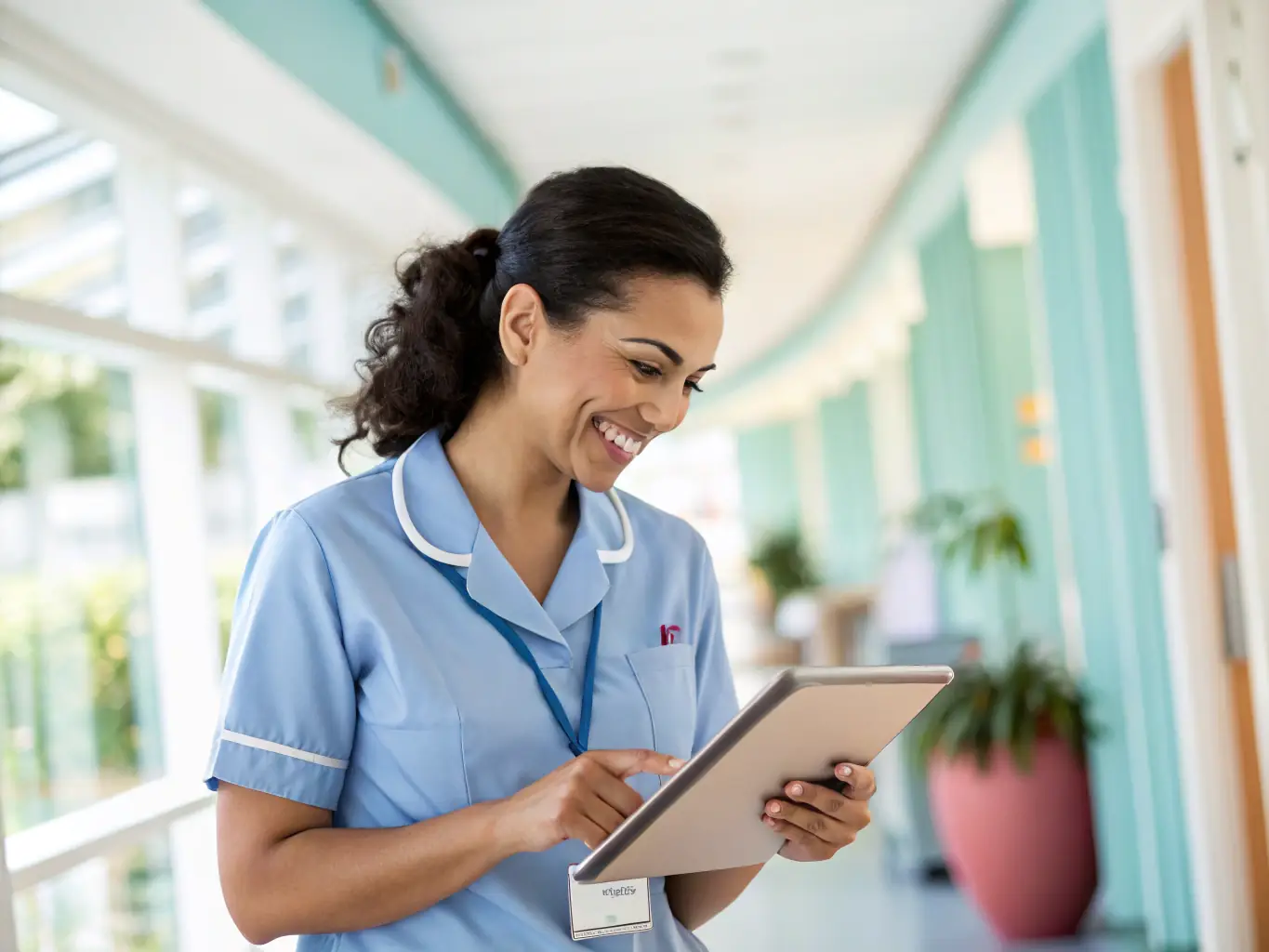 A Certified Nursing Assistant (CNA) using Careflownote on a tablet in a brightly lit nursing home setting, smiling as they efficiently document patient care details.